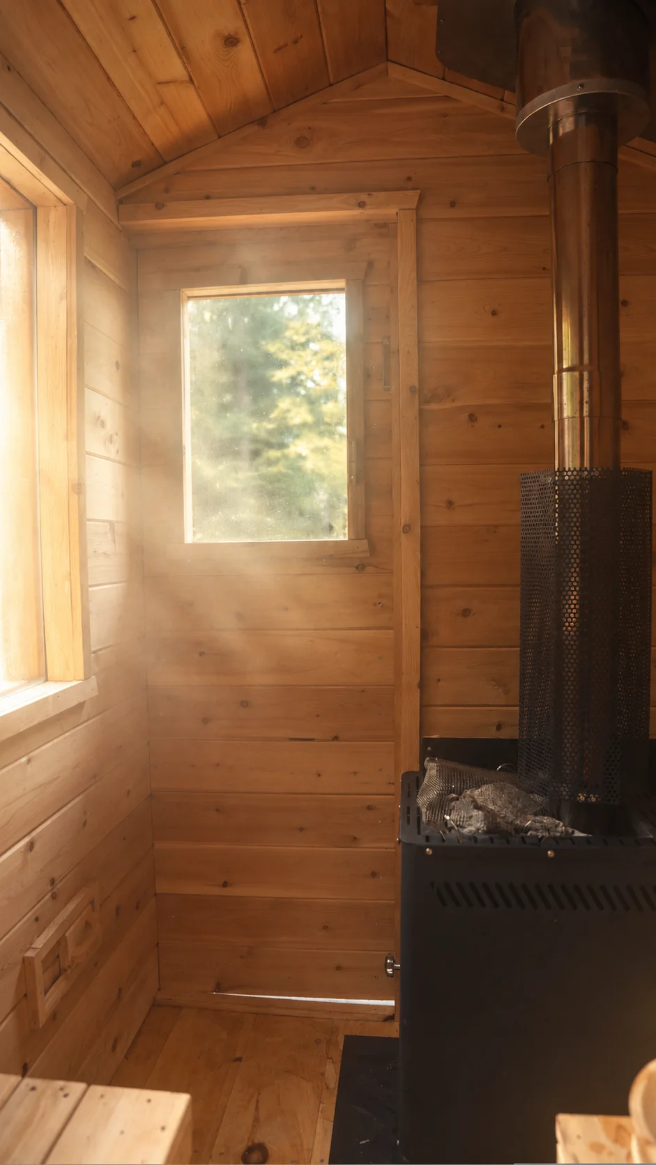 Sunlight and steam fill the wooden sauna interior