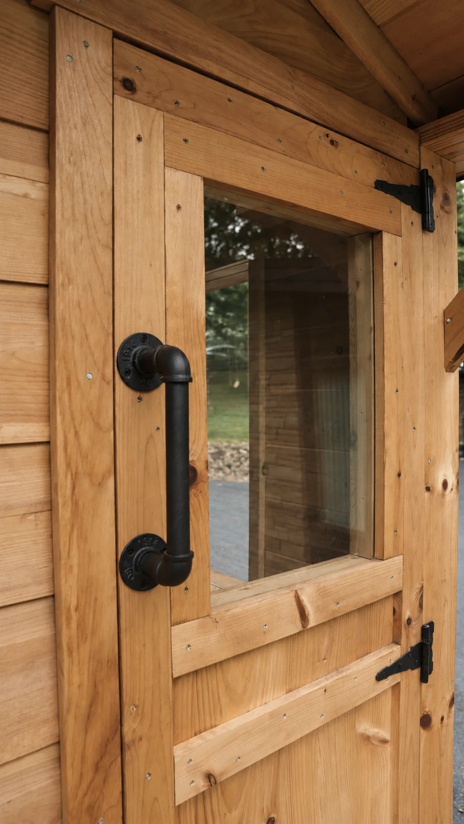 Wooden sauna door with a black handle and a window into the interior