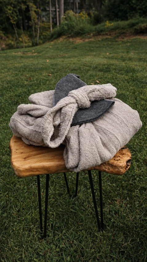 Soft robes and felt hats arranged on a wooden stool