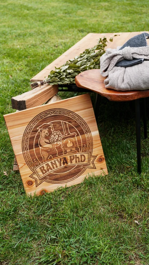 Engraved Banya PhD bear sign beside wood, leaves and robes