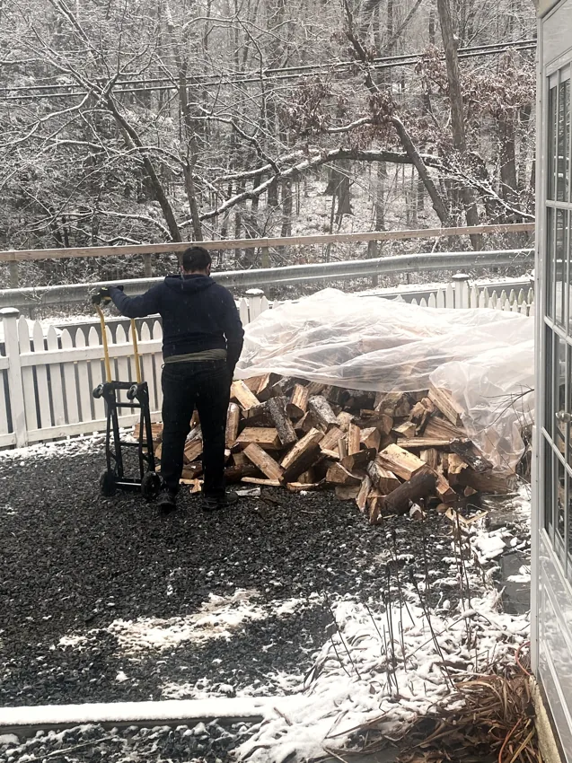 Adam beside stacked firewood in winter